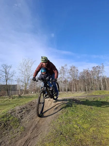 Adult and child riding a mountain bike on a dirt path